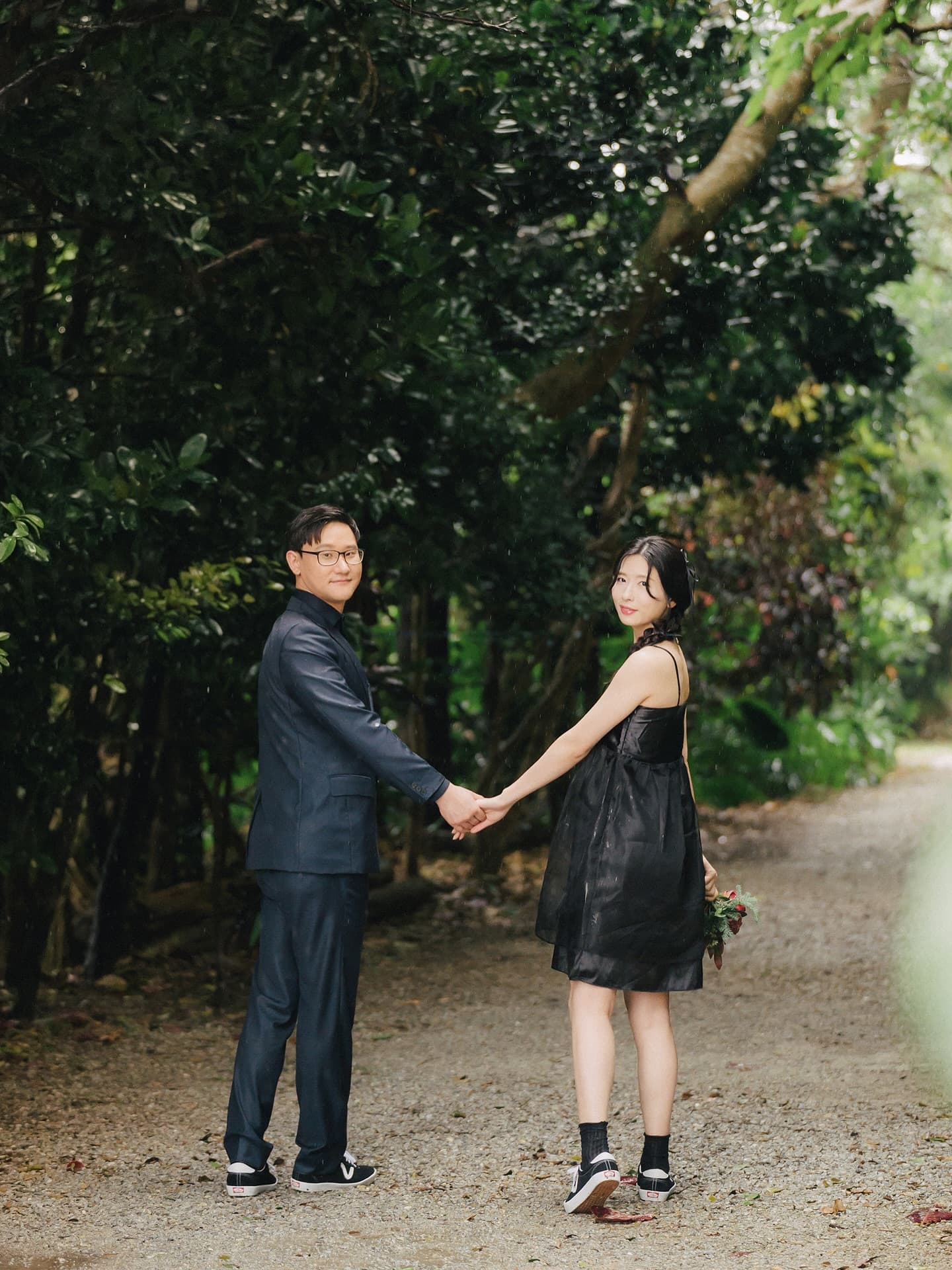 Couple in black strolling hand in hand down a leafy Okinawa lane