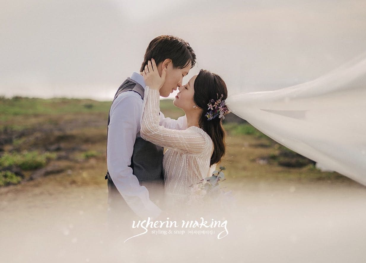 바람에 날리는 베일 속에서 입 맞추는 신랑 신부