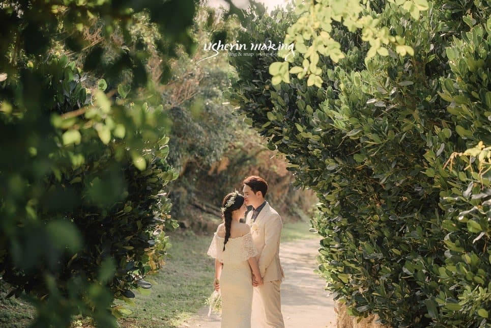 역광이 쏟아지는 초록 숲길에서 입 맞추는 신랑 신부