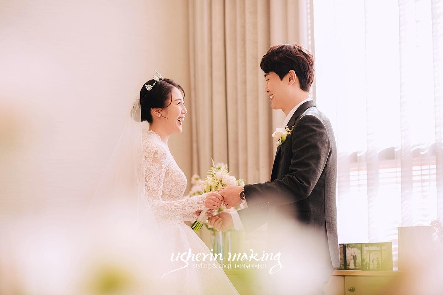 Bride in a veil and groom laughing hand in hand in a softly lit room