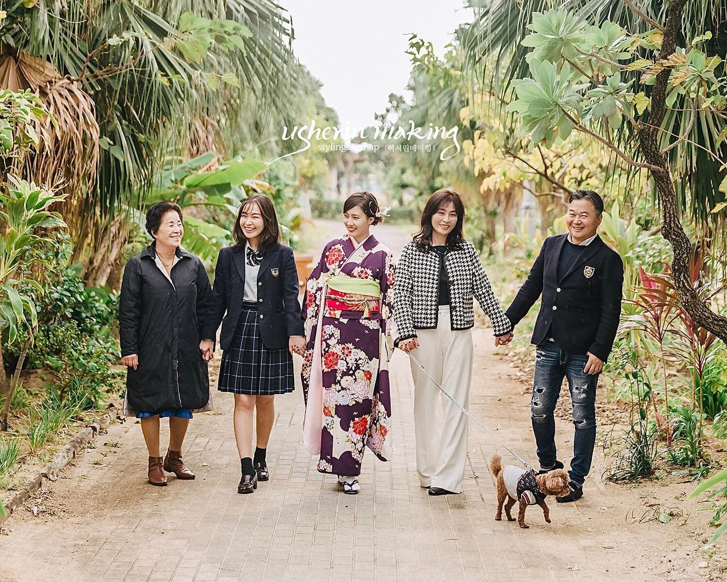 오키나와 야자수 길을 보라색 기모노 차림 딸과 함께 걷는 가족과 반려견