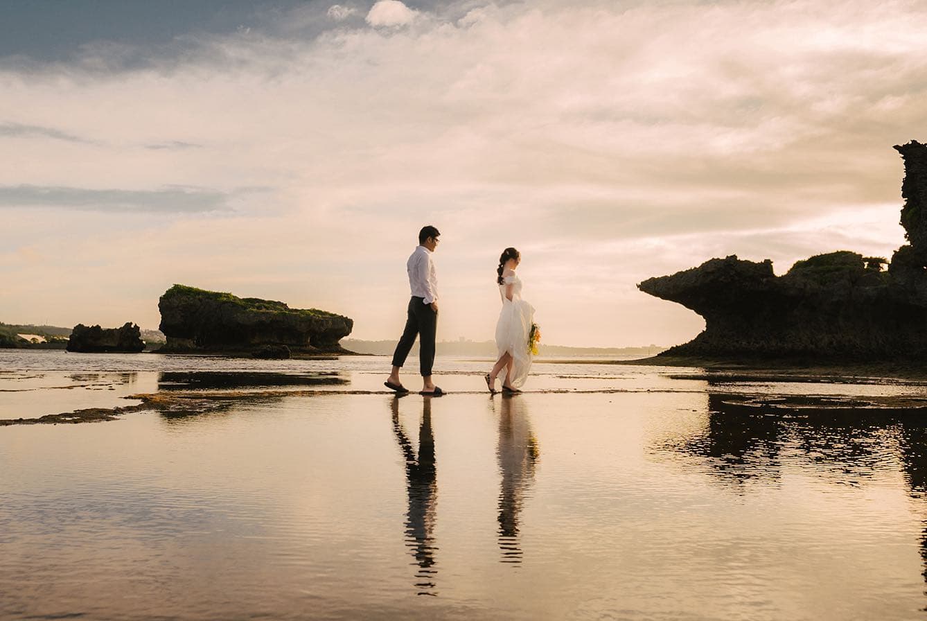 Bride and groom walking on a mirror-like tidal beach in Okinawa