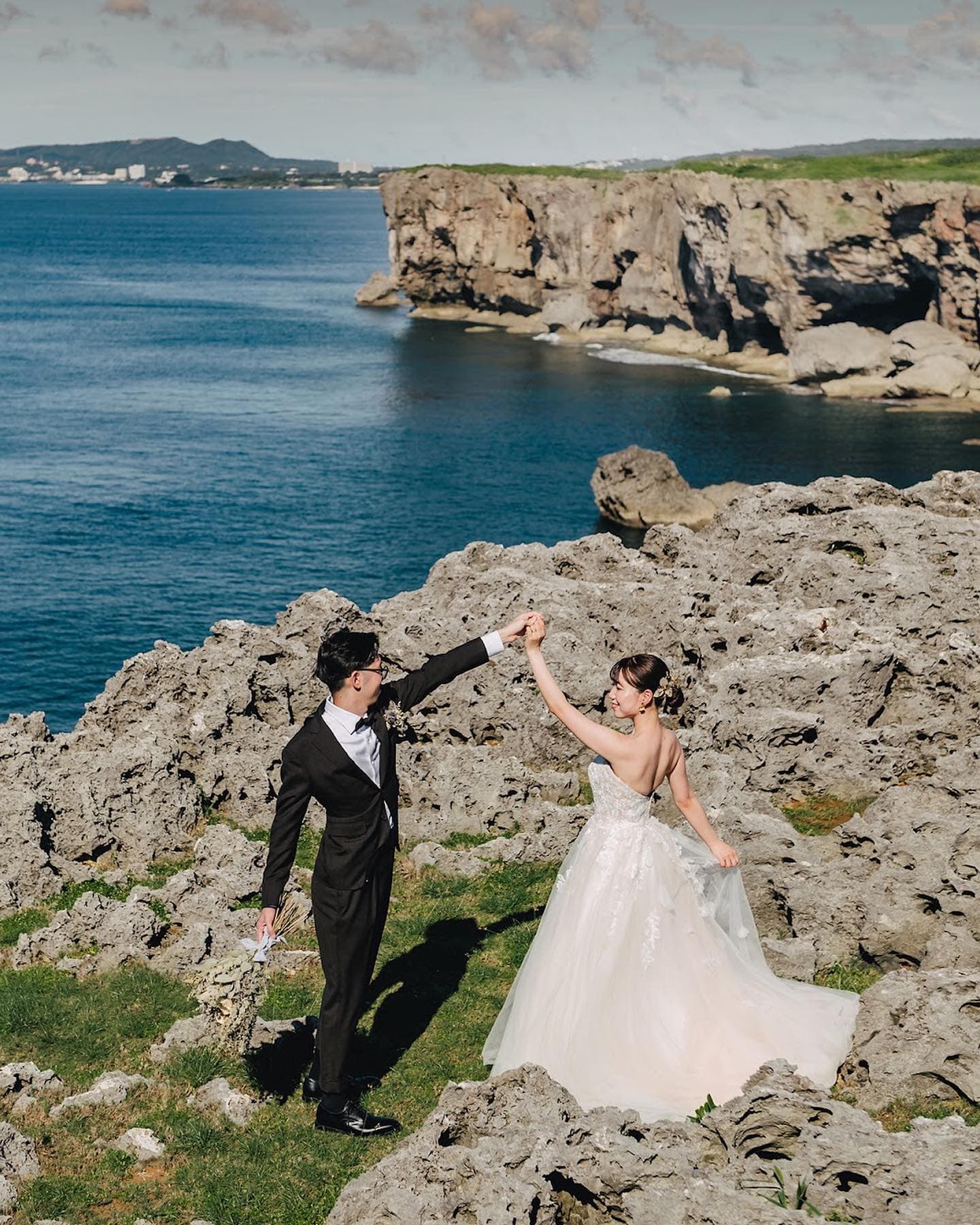 断崖と紺碧の海を背に、手を取り合って踊る新郎新婦