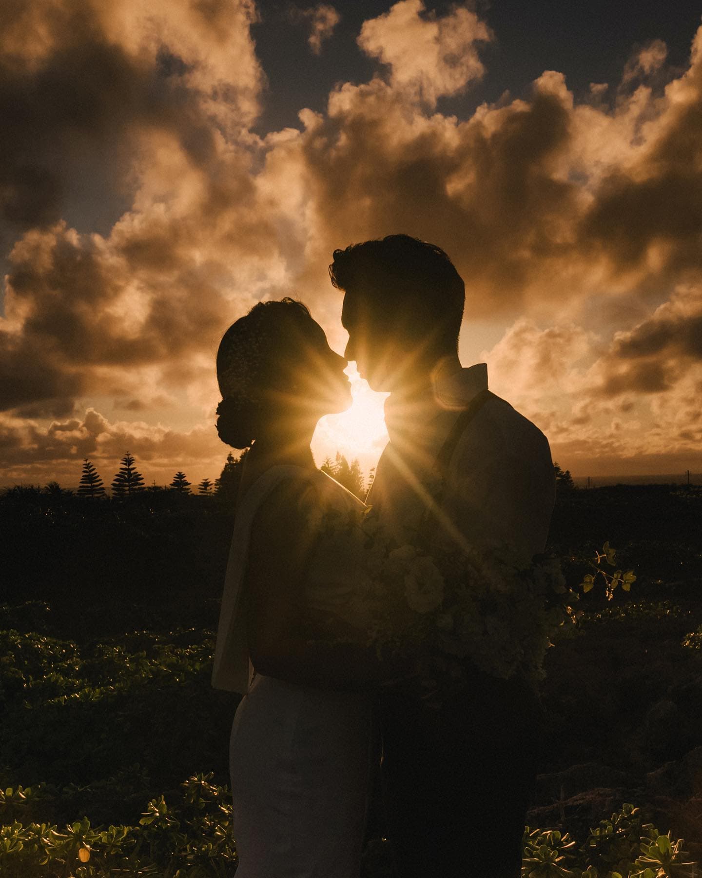 A couple's silhouette kissing before dramatic sunset clouds in Okinawa