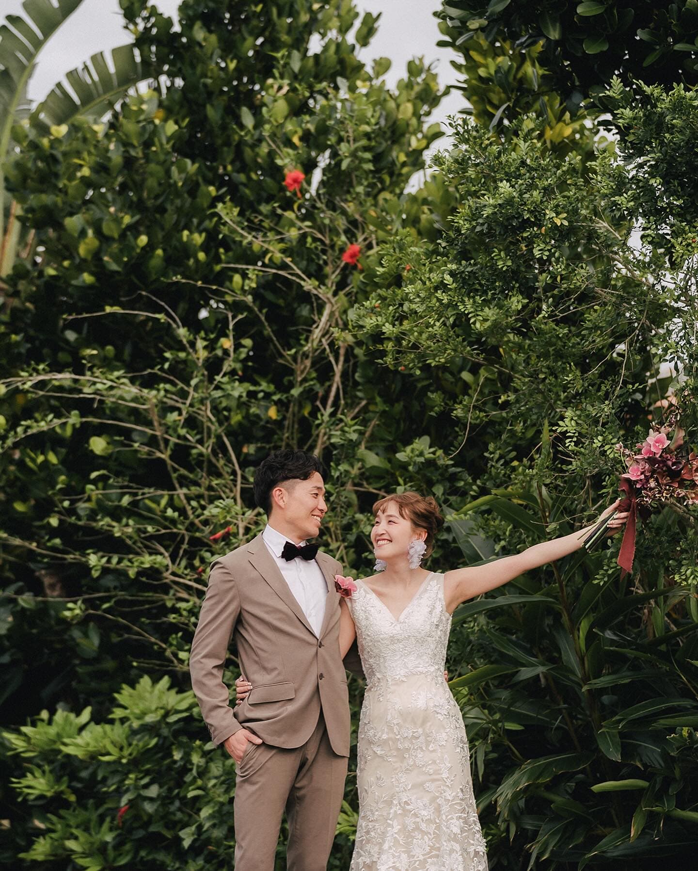 Couple smiling amid lush green foliage in Okinawa
