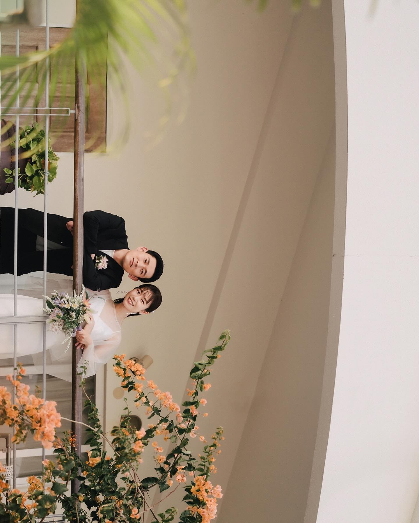Newlyweds on a white staircase behind orange bougainvillea, Okinawa