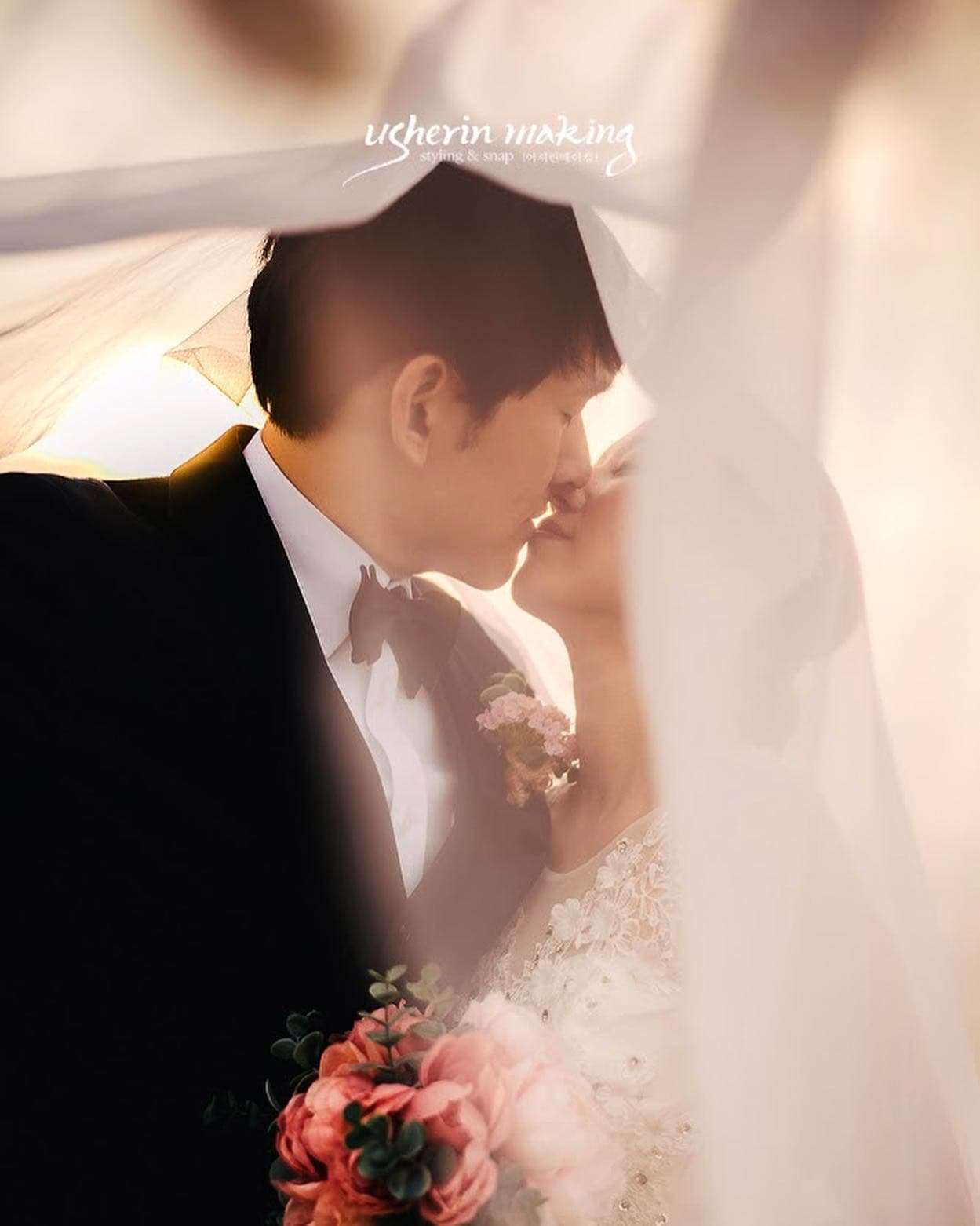 드리운 베일 사이로 입맞춤하는 신랑신부의 클로즈업