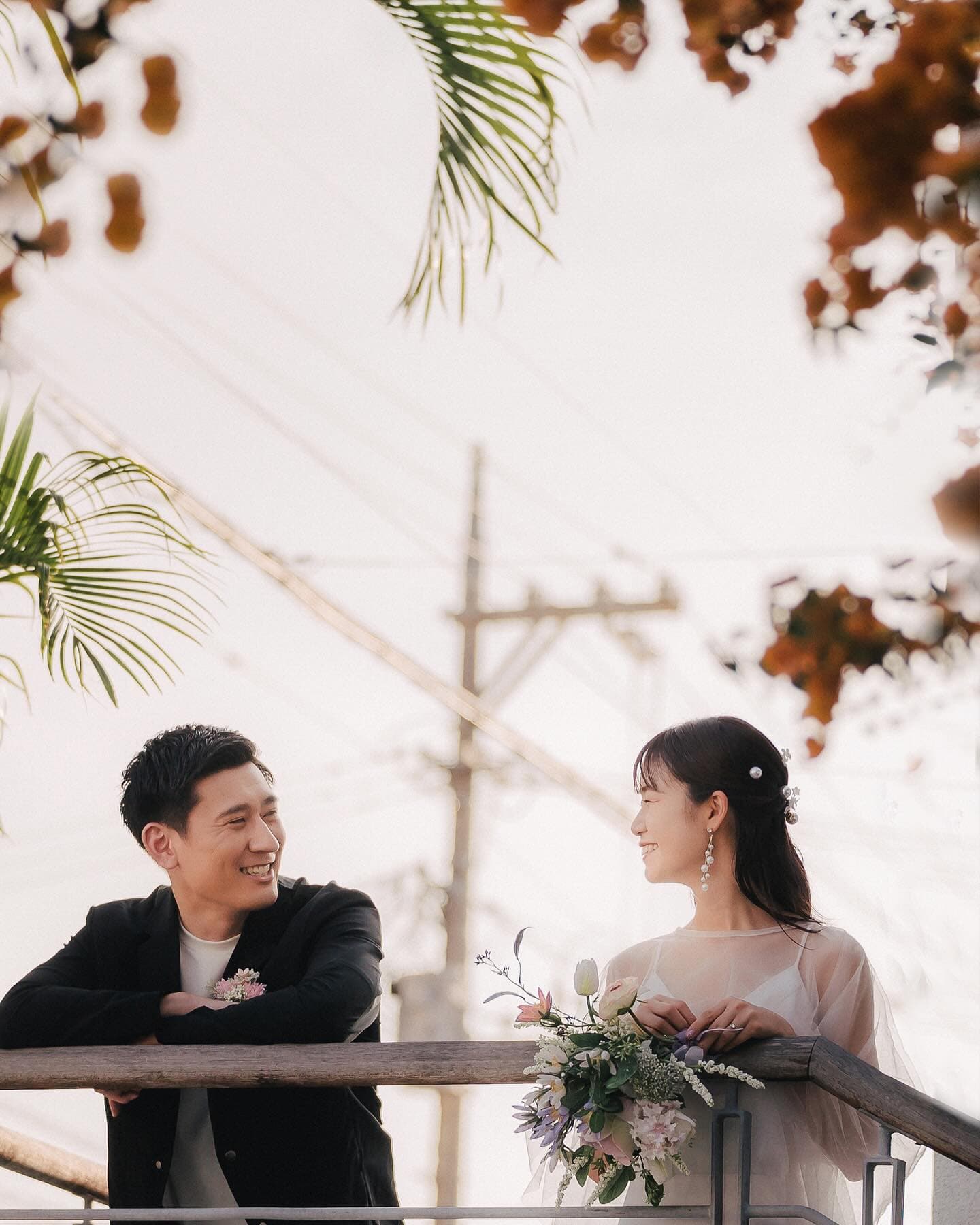 Bride and groom on a balcony framed by orange bougainvillea, Okinawa