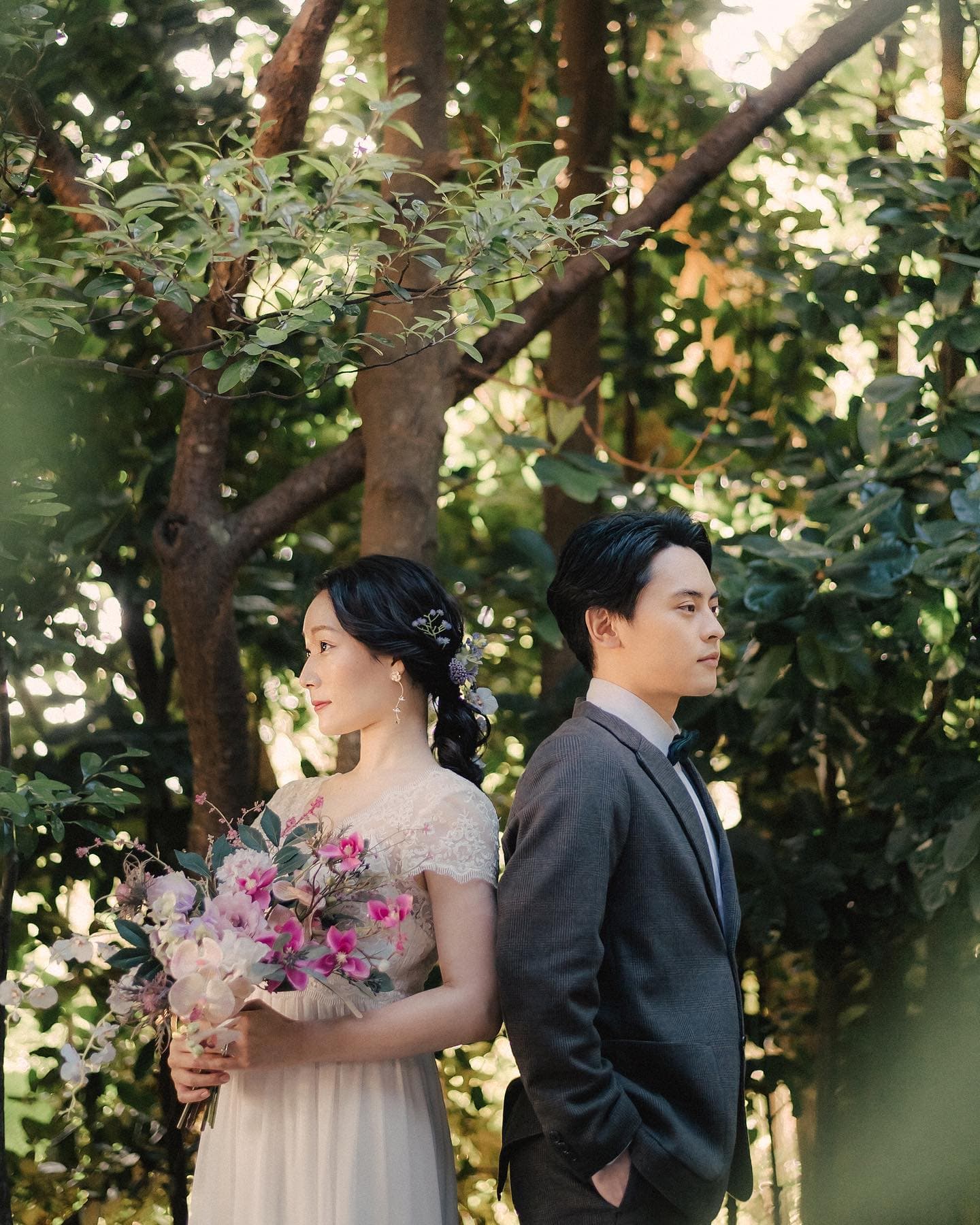 木漏れ日の森で背中を合わせて立つ新郎新婦