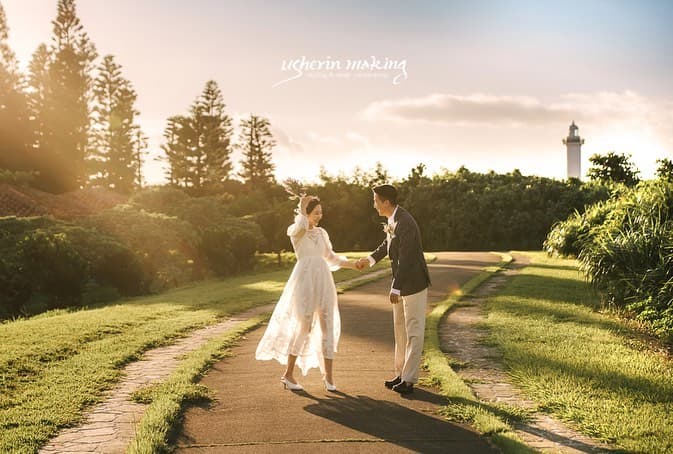 灯台の見える夕日の道で、手を取り合う沖縄の新郎新婦