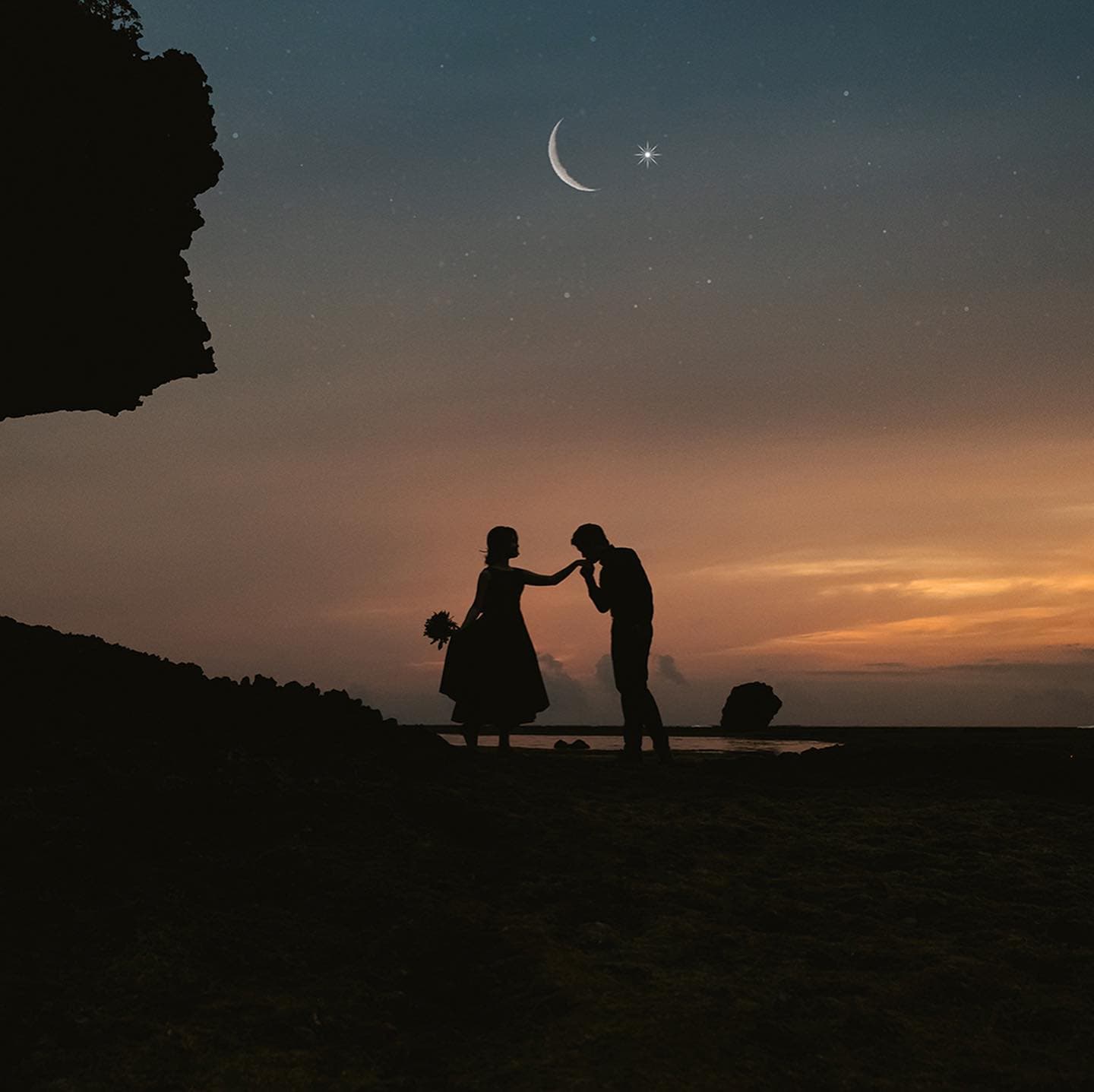 三日月と星の下、夕暮れの海辺で手にキスするカップルのシルエット、沖縄