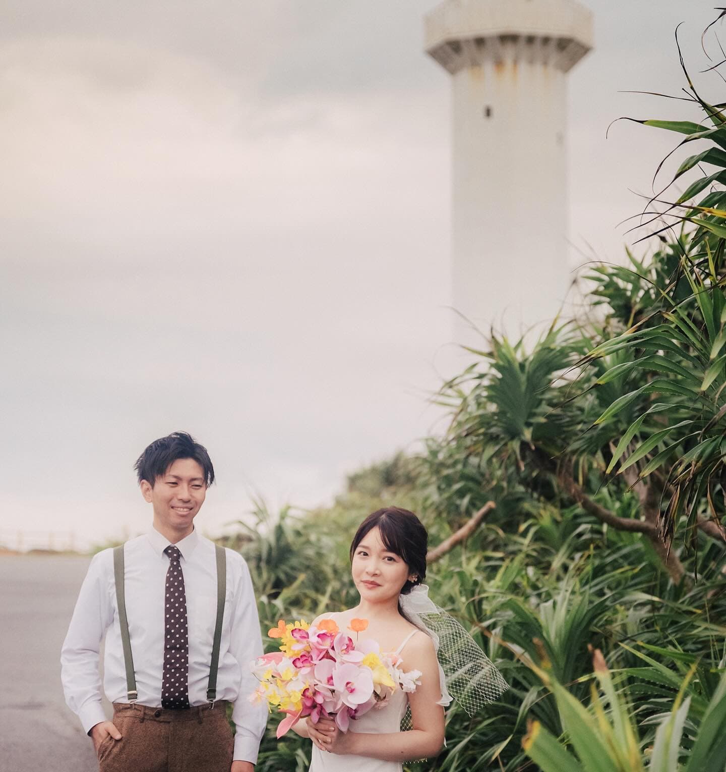 Couple beside tropical greenery with a Miyakojima lighthouse behind
