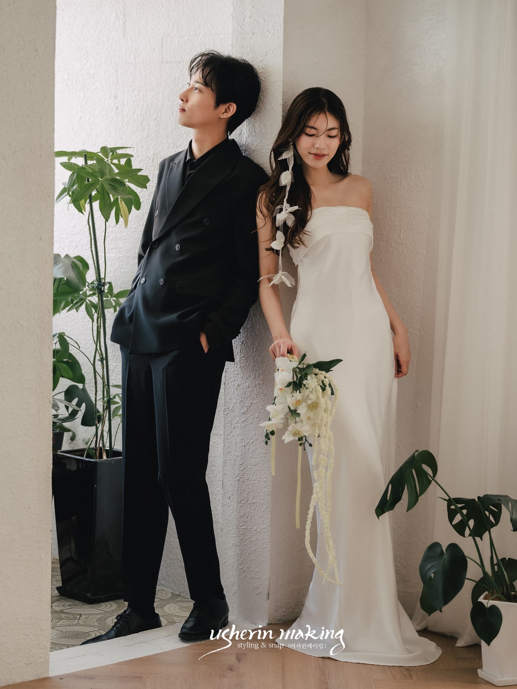 Groom in black and bride in a white dress pose in a Korean-style studio