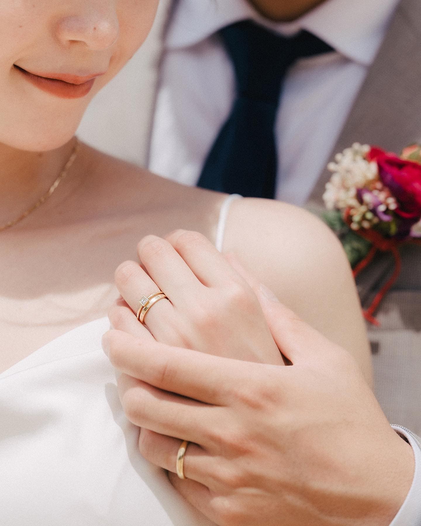 結婚指輪を重ねた新郎新婦の手元のクローズアップ