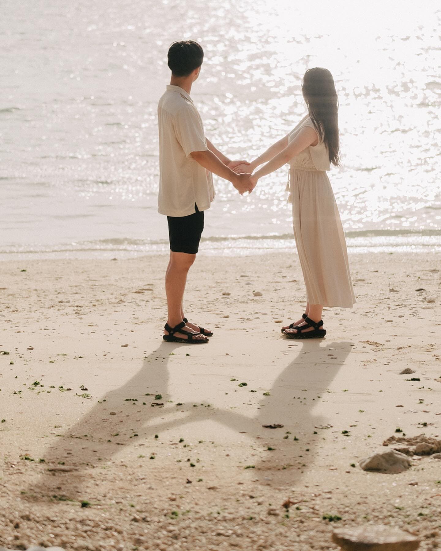 역광의 백사장에서 두 손을 맞잡고 마주 선 커플, 오키나와
