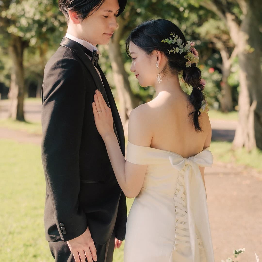 花を編み込んだヘアの花嫁が新郎の胸に手を添えるクローズアップ。
