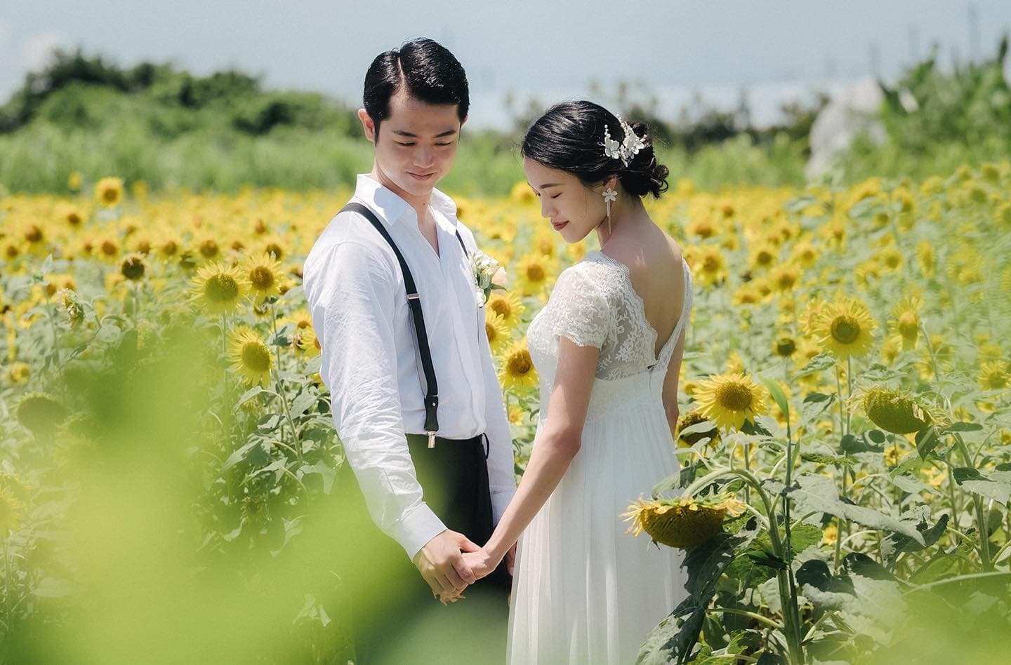 Bride and groom holding hands in a blooming sunflower field in Okinawa