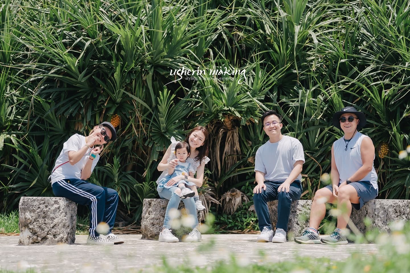 Family smiling on stone stools before lush tropical greenery in Okinawa