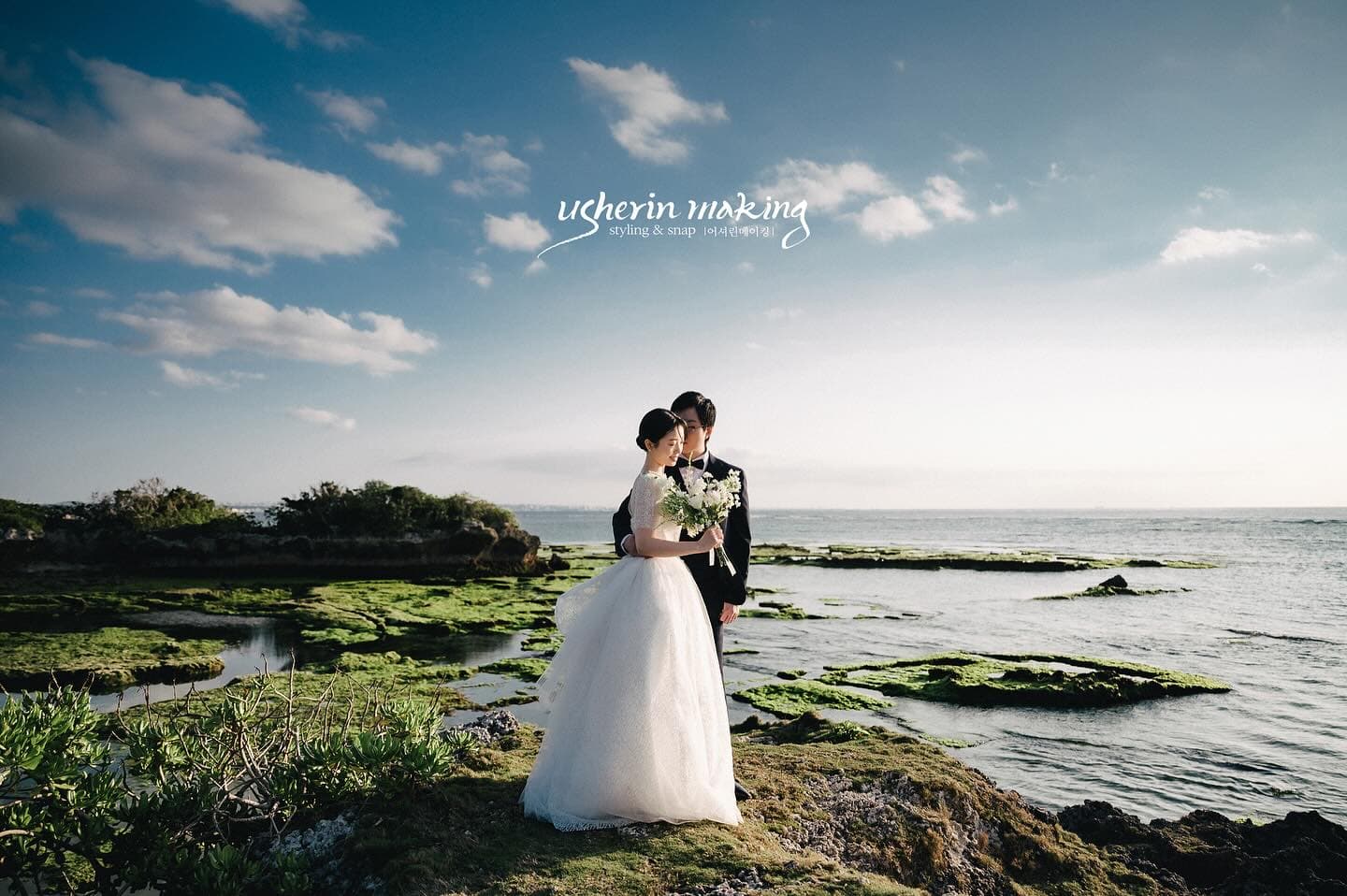 Back view of a couple gazing at the sea from mossy rocks in Okinawa