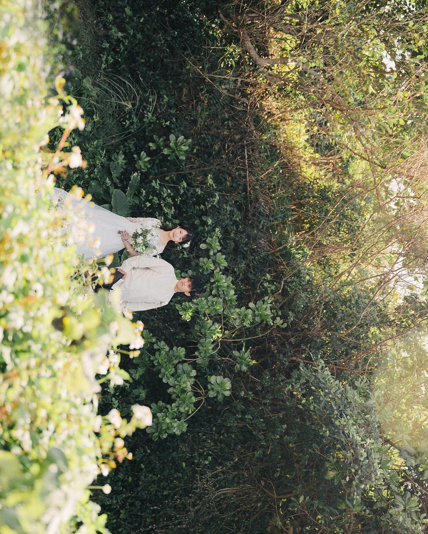 Couple making their way through dense green foliage in Okinawa
