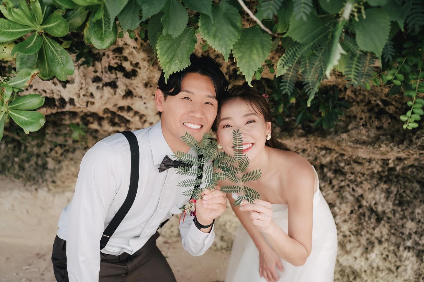 초록 잎사귀를 들고 얼굴을 맞대 웃는 신랑신부, 오키나와