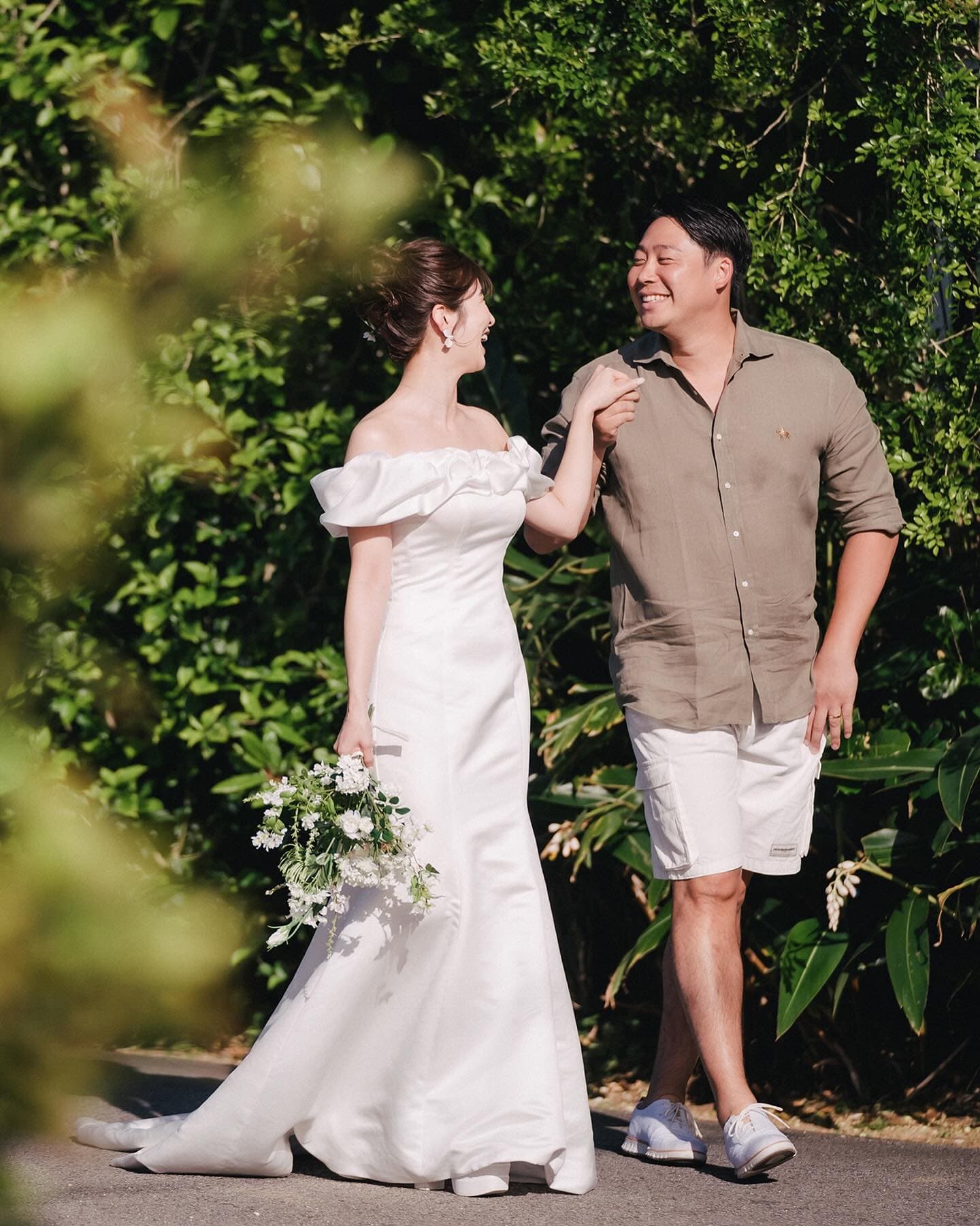 Laughing couple strolls along a sunlit green path in Okinawa