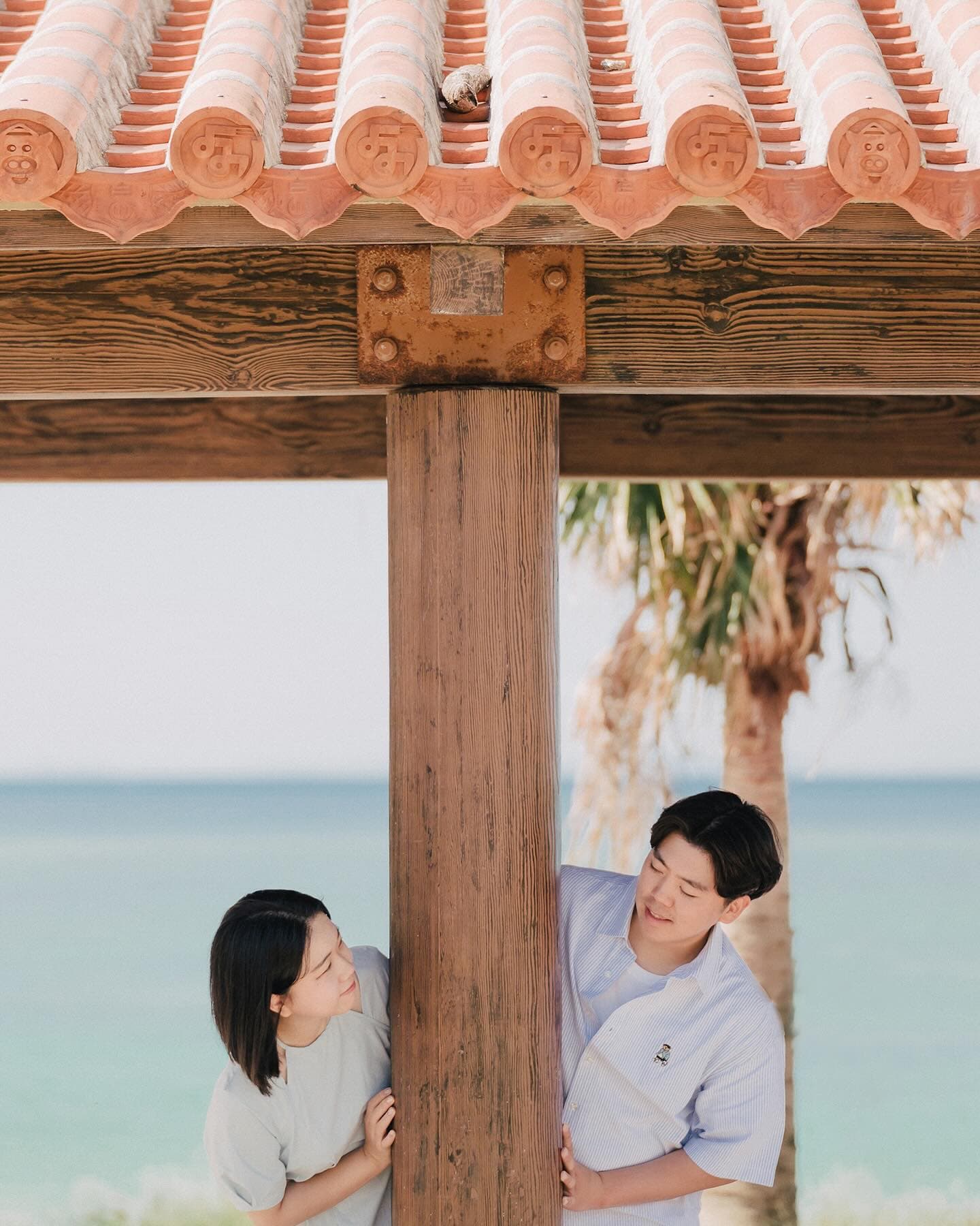 붉은 기와 정자 기둥 사이로 마주 보는 커플, 오키나와 바다와 야자수