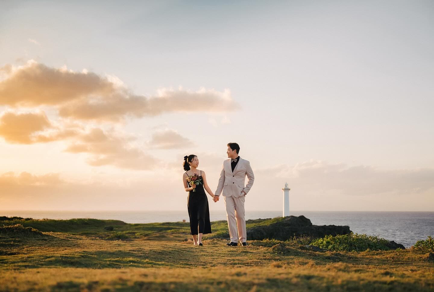 Couple walking hand in hand on a cape by an Okinawa lighthouse