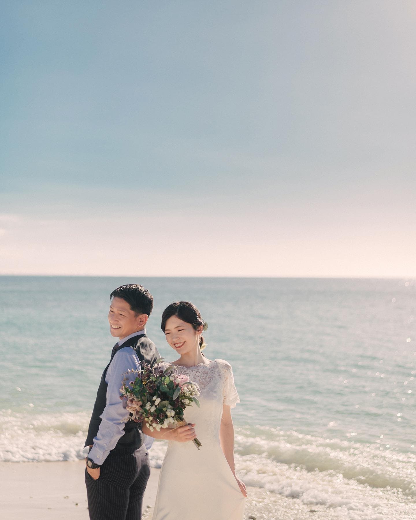 Smiling couple with a bouquet before the sparkling Okinawa sea