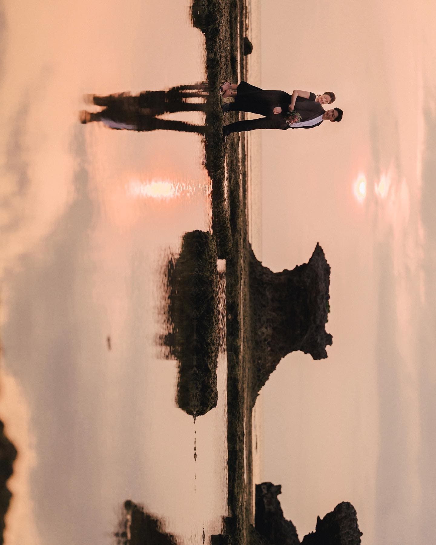 Couple mirrored in shallow water under a glowing sunset, Okinawa