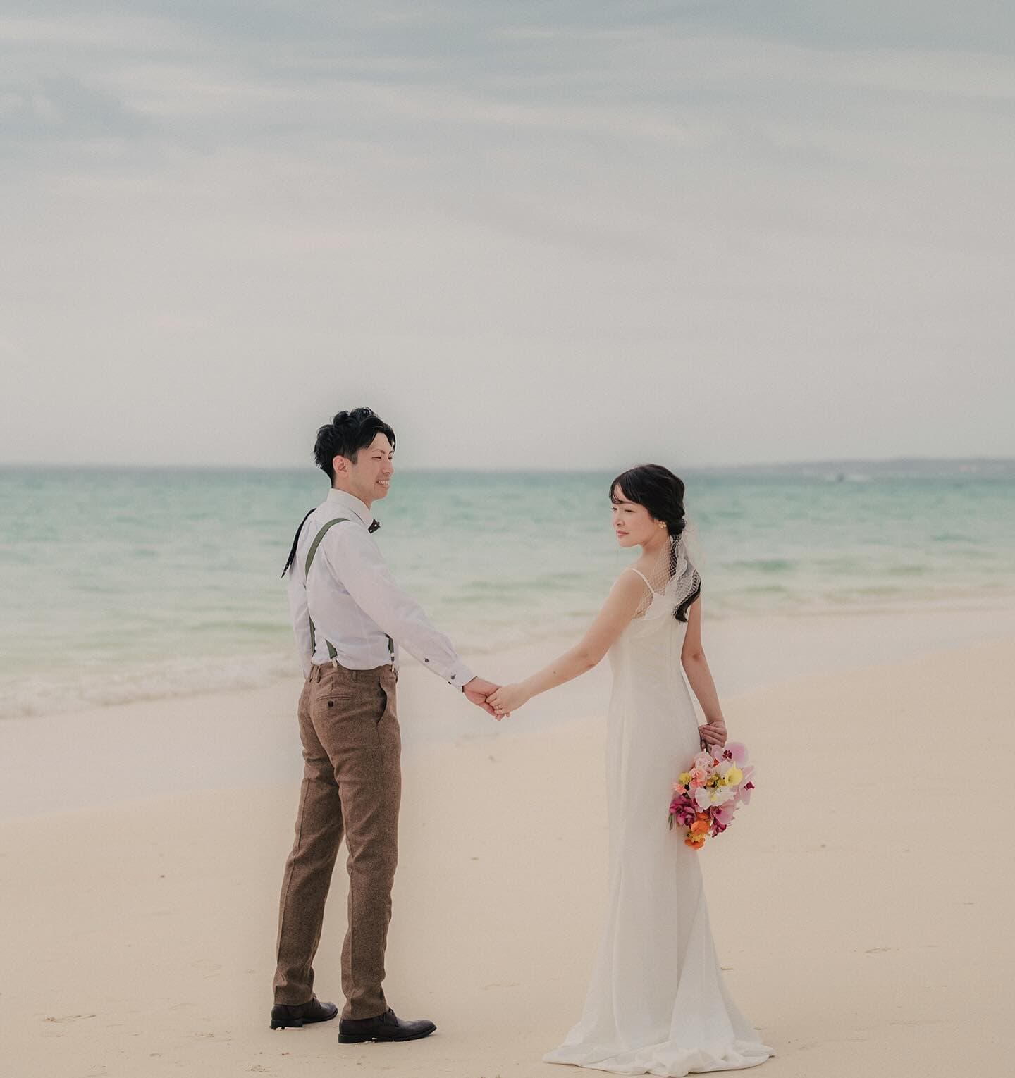 Couple holding hands on a white-sand beach in Miyakojima