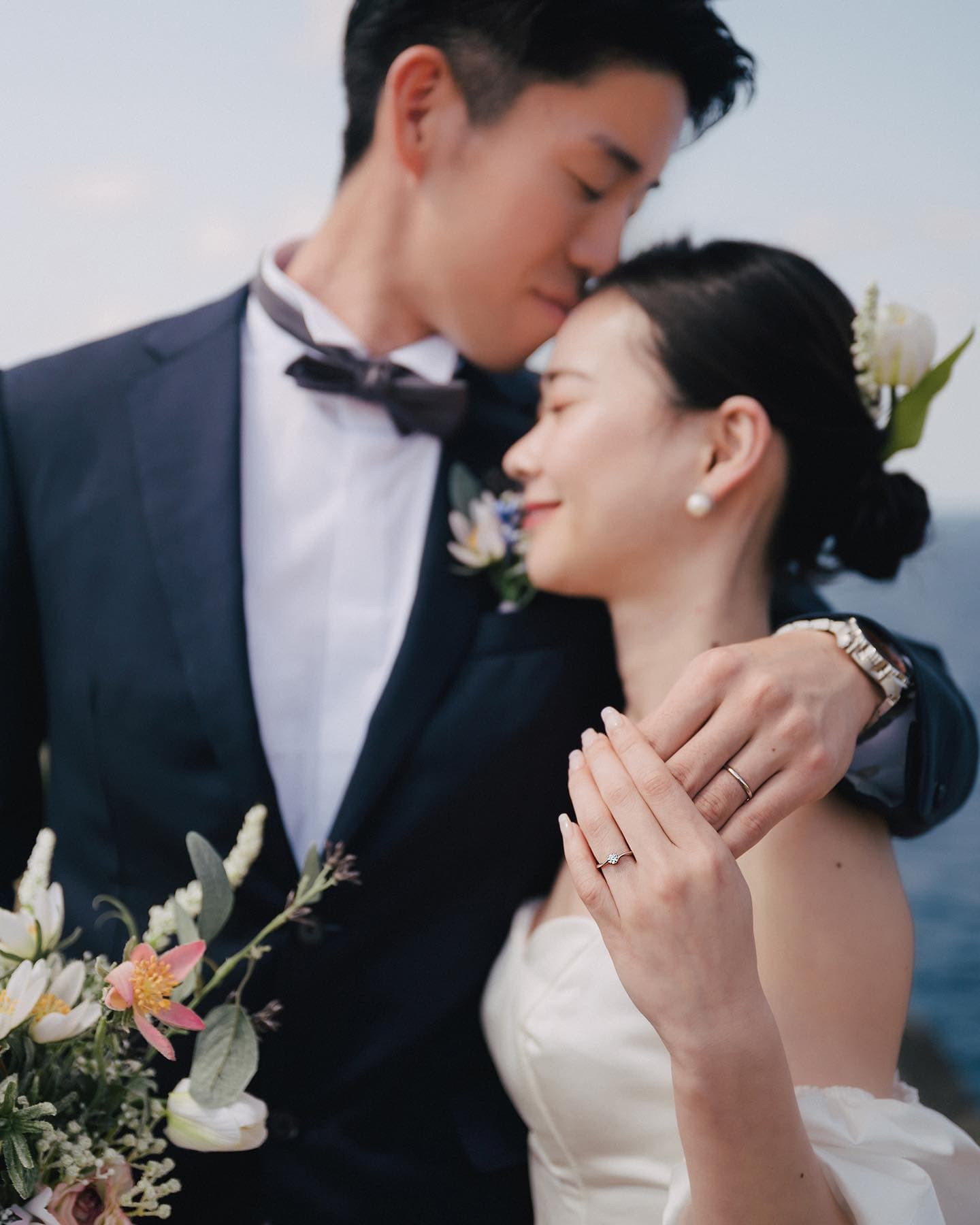 結婚指輪をつけた手を添えて寄り添う新郎新婦のクローズアップ、沖縄