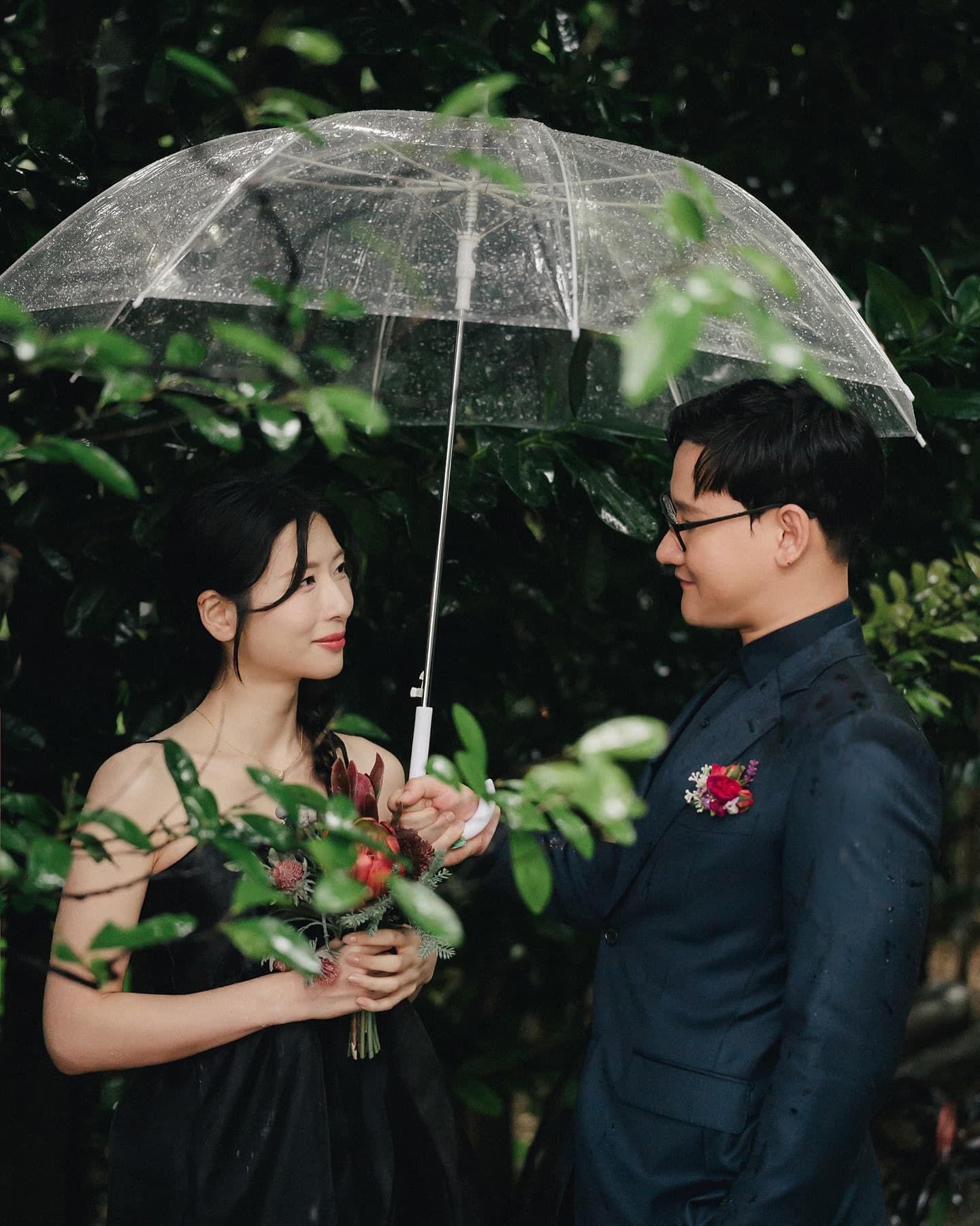 Couple sharing a clear umbrella in the rain on an Okinawa shoot