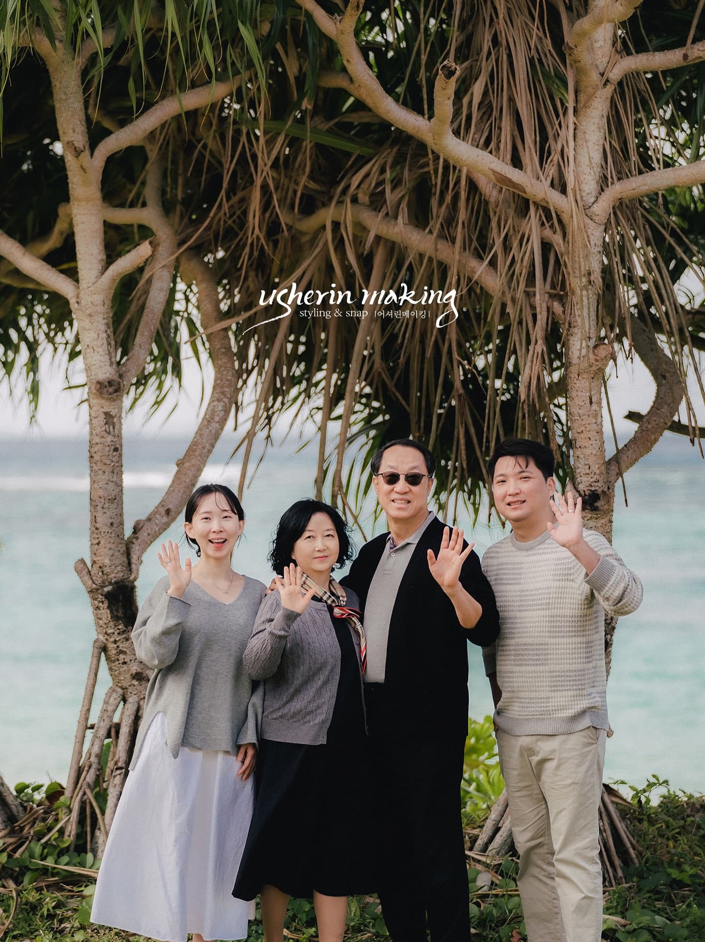 Family of four waving under seaside pandanus trees in Okinawa