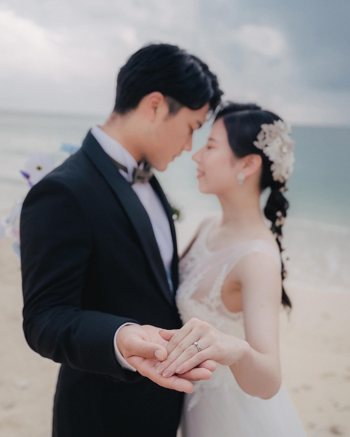 Couple gazing at each other with clasped hands, ring catching the light, Okinawa