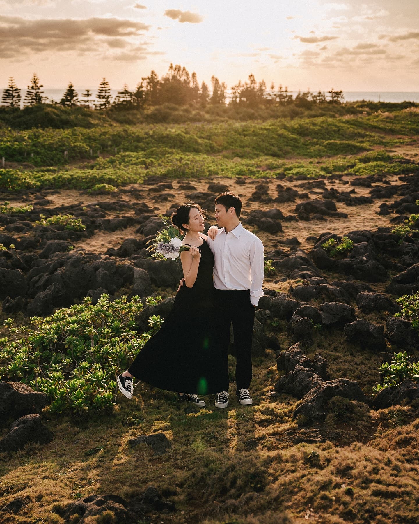 Couple leaning close among rocky fields at sunset during an Okinawa pre-wedding shoot