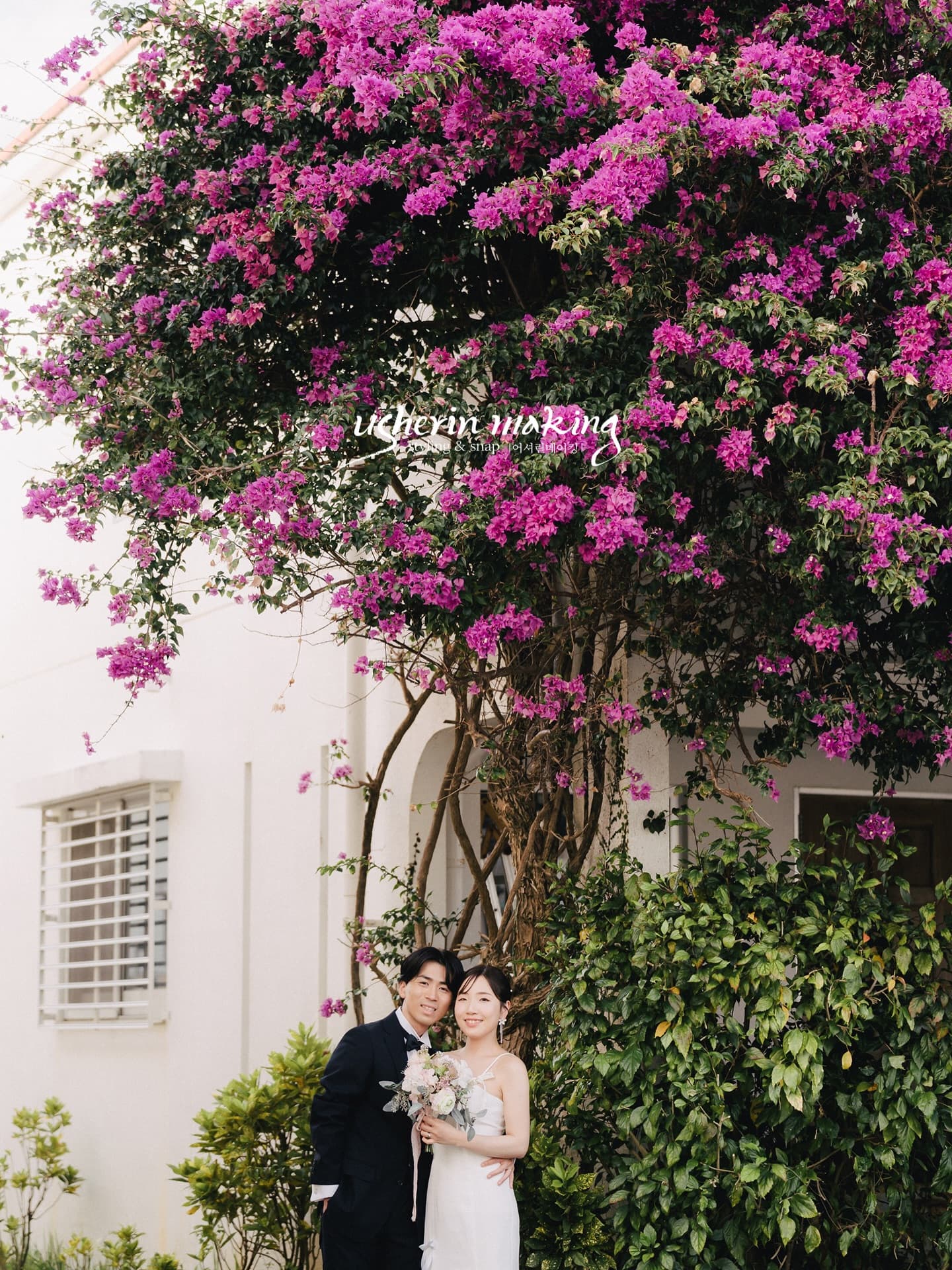 Couple beneath bougainvillea in full bloom over a white house in Okinawa