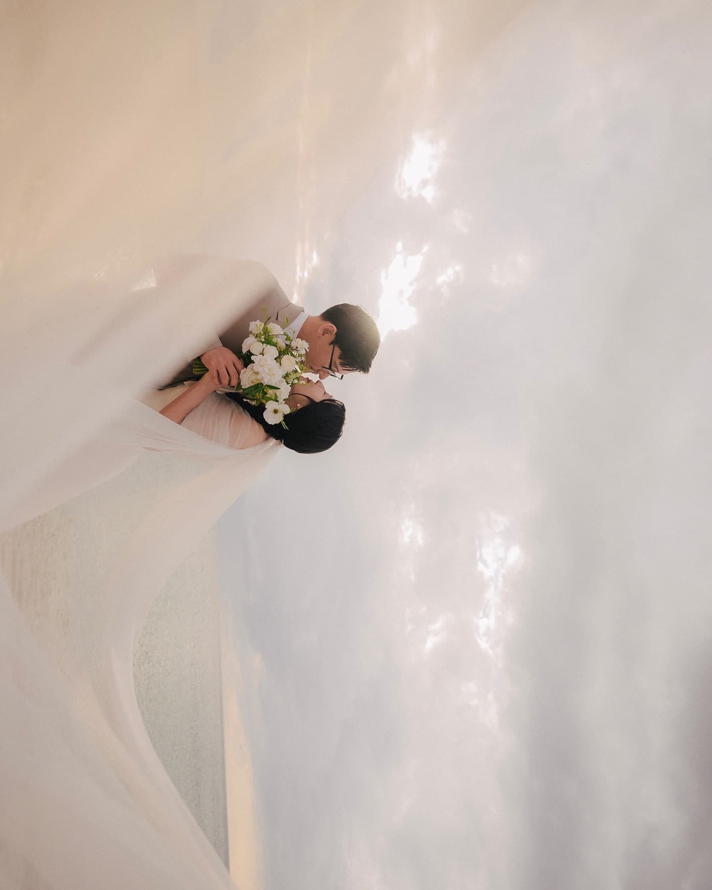Close-up of a couple kissing beneath the veil against Okinawa's glowing evening sky
