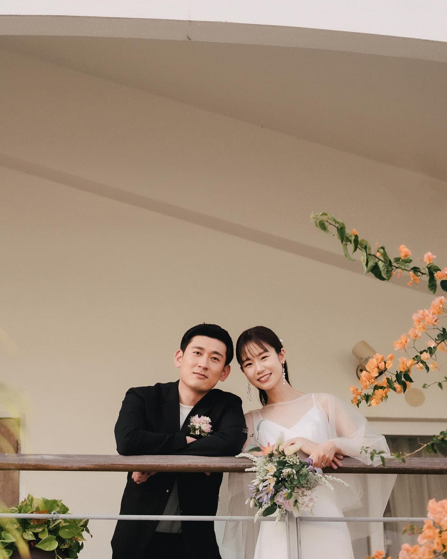 Couple leaning on a balcony rail at dusk beside bougainvillea, Okinawa