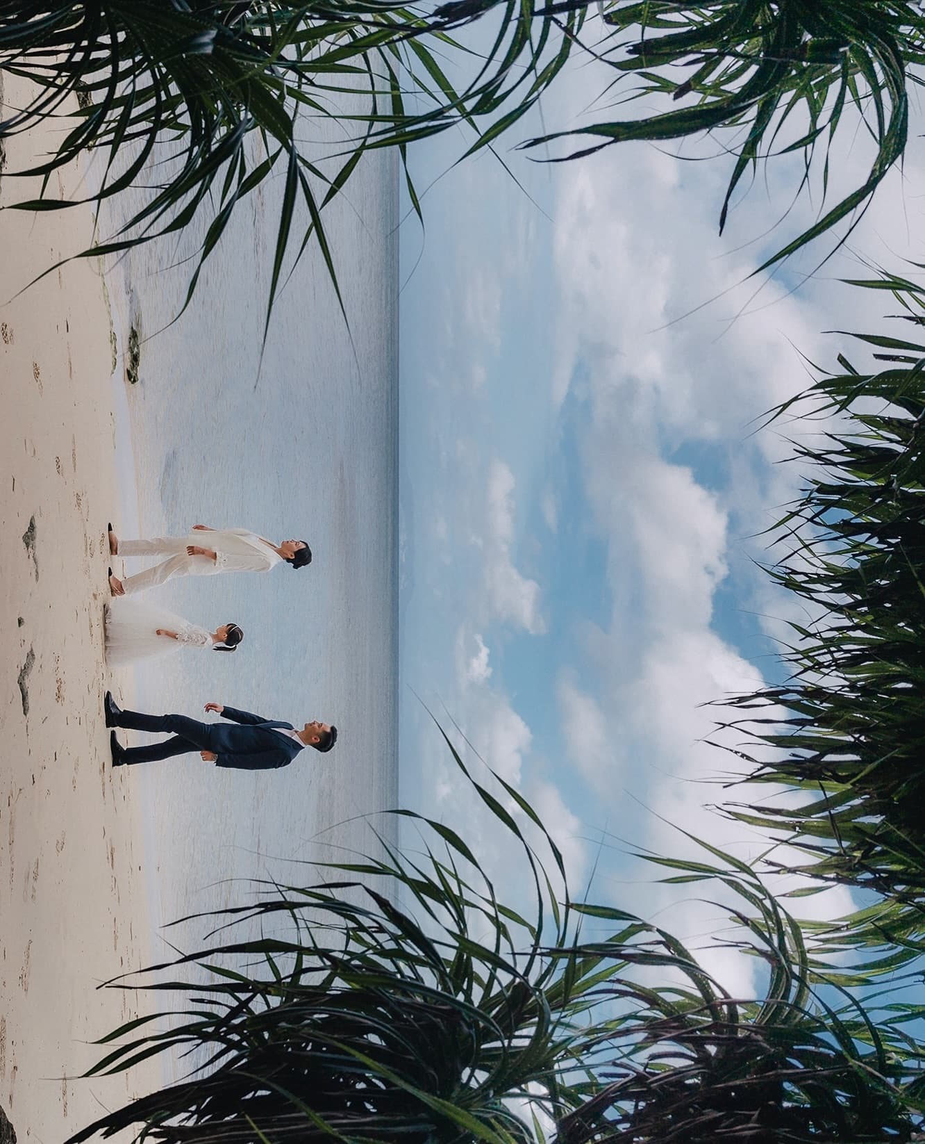 Family of three walking along a white Okinawa beach under a bright blue sky