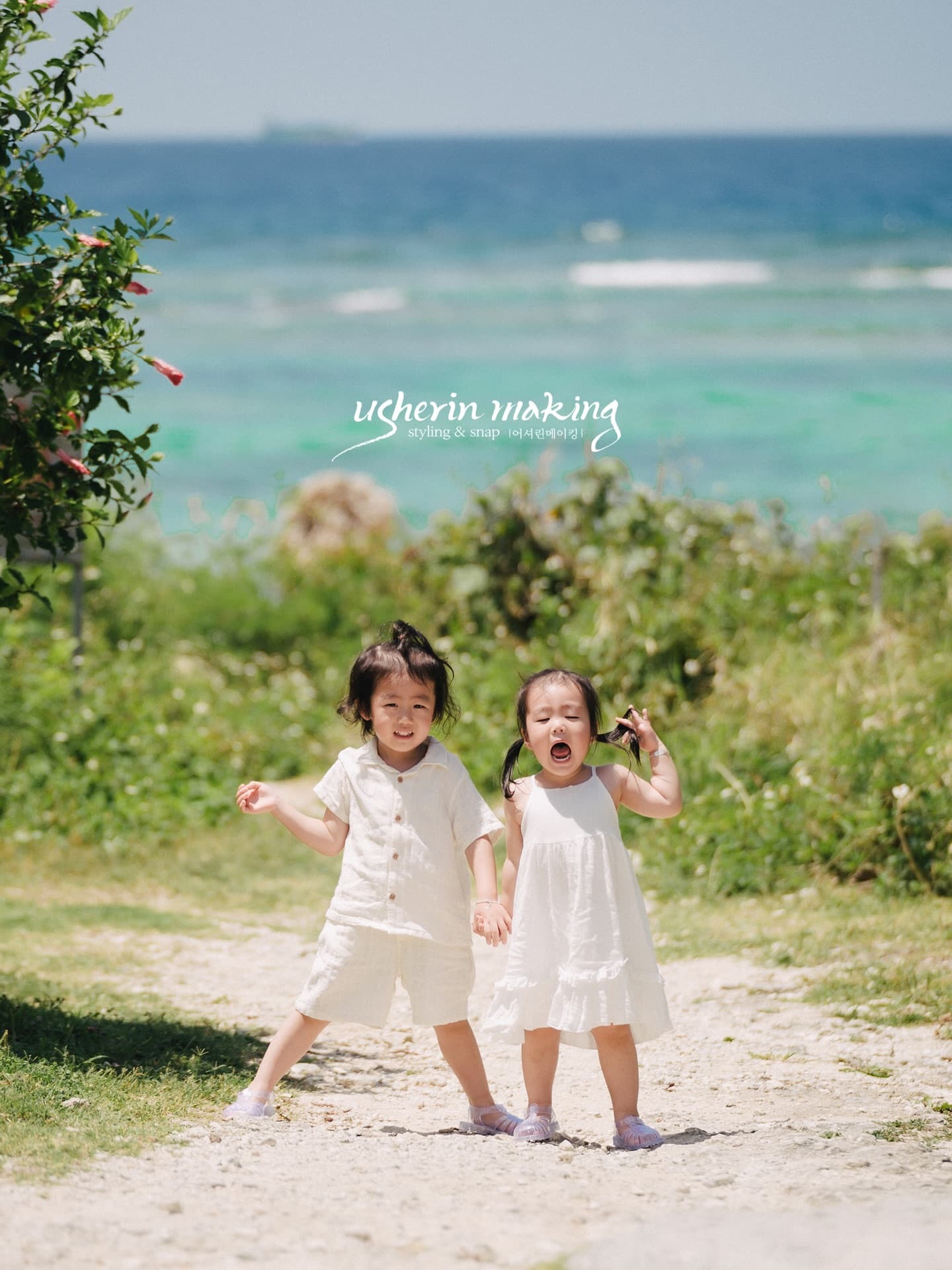 Two children hold hands and laugh by the emerald sea in Okinawa
