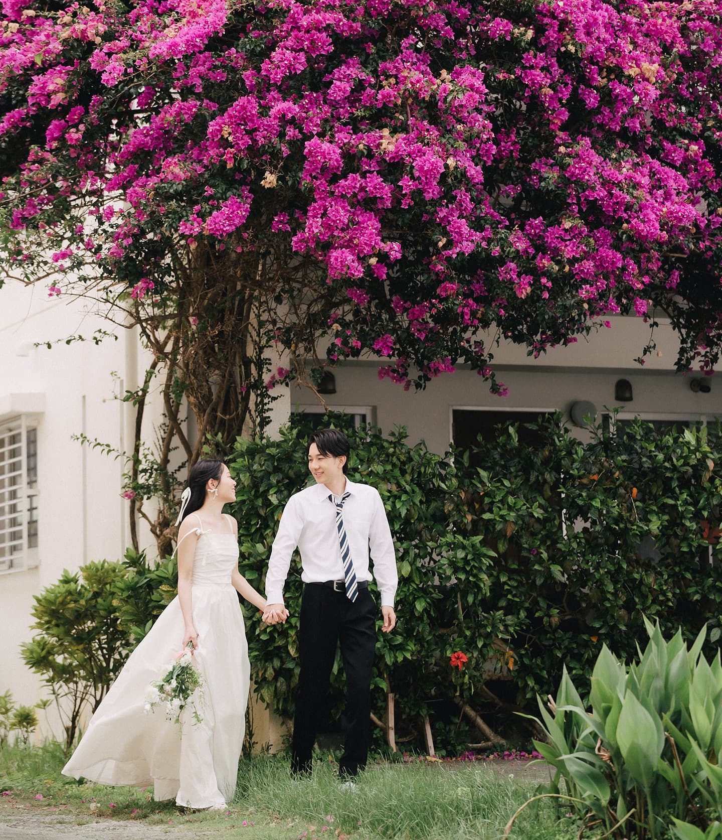 Couple holding hands under blooming bougainvillea on an Okinawa street