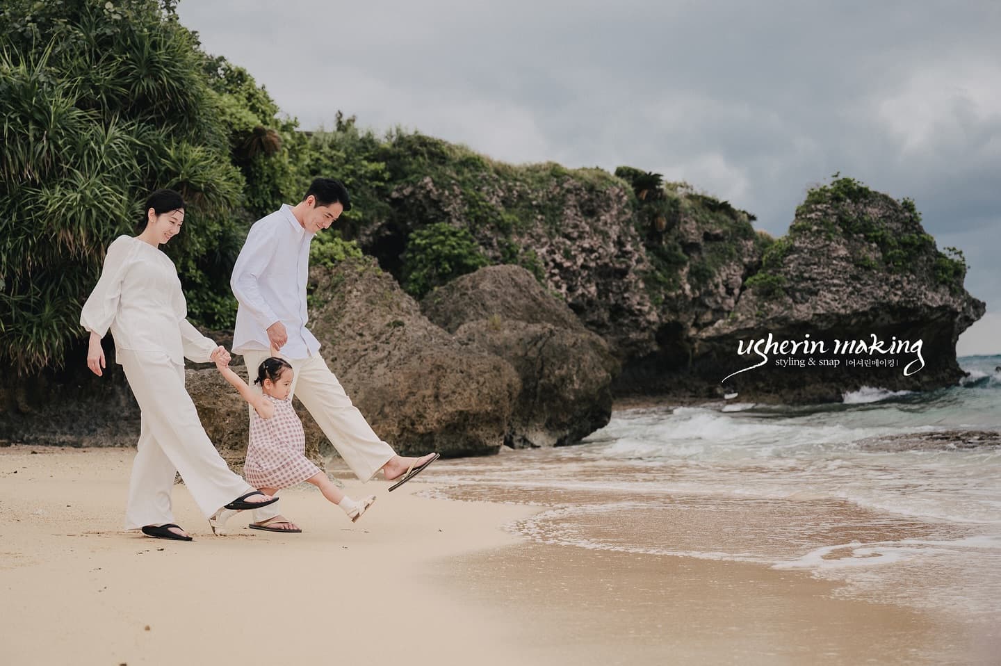 Parents walking hand in hand with their little daughter on a rocky Okinawa beach