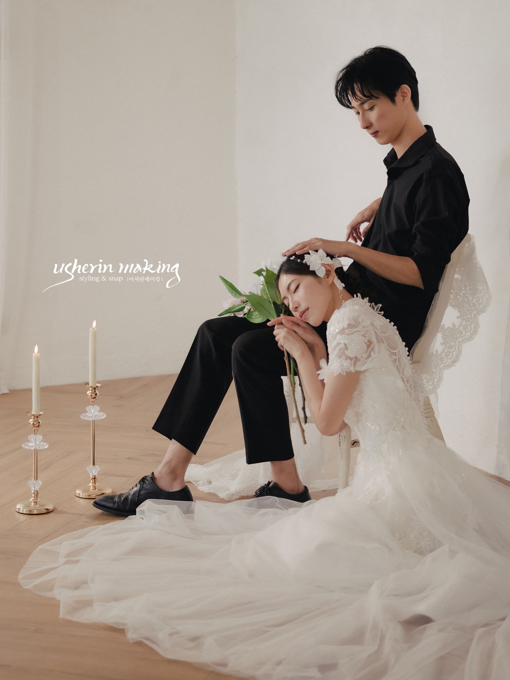 Bride resting against the seated groom's knee holding white tulips, candles lit in the studio