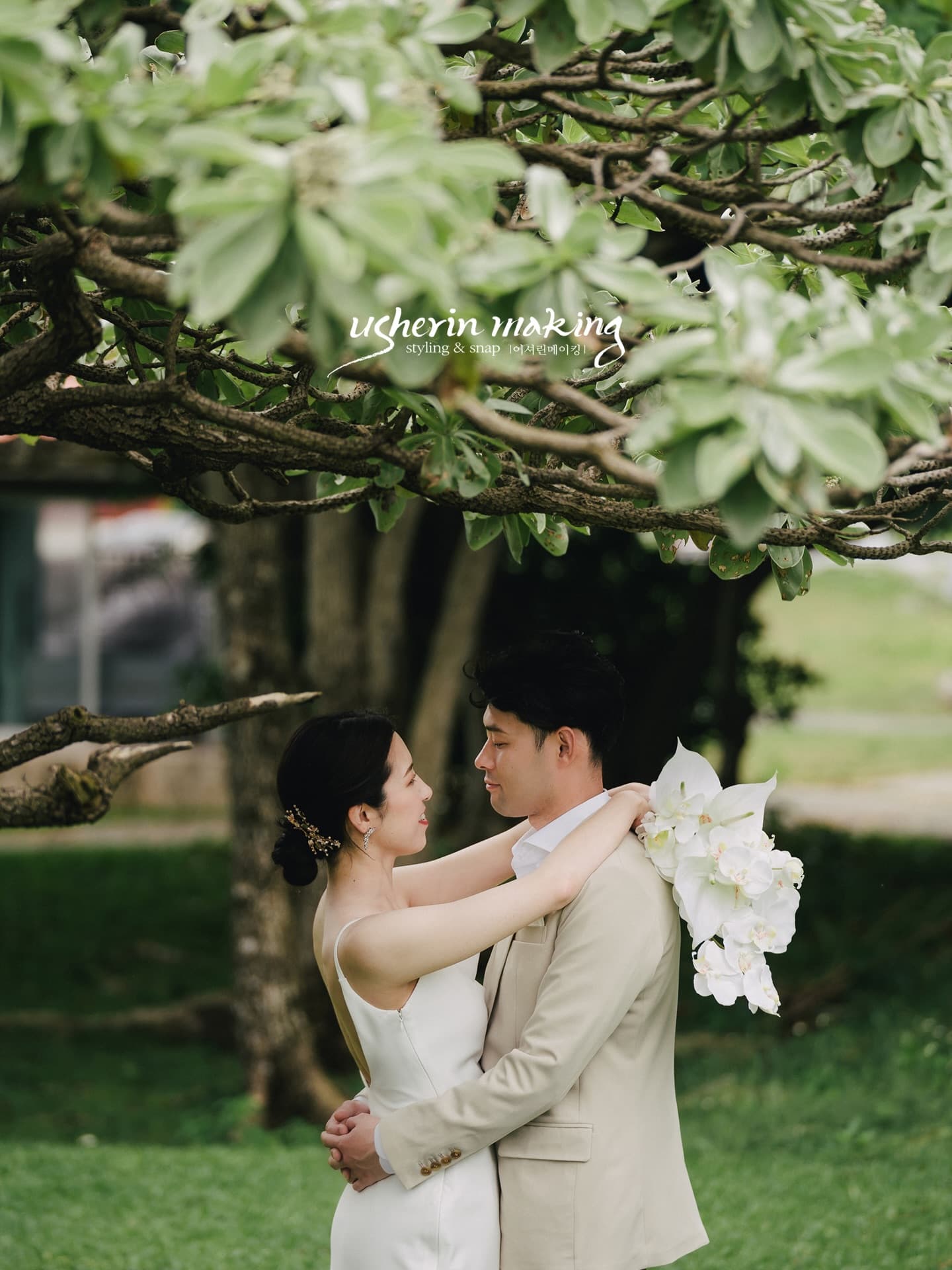 Couple embracing under a big green tree with white orchids in Okinawa