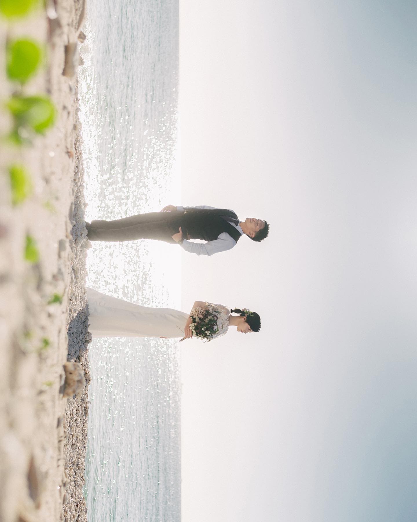 Bride and groom standing on a glittering Okinawa shoreline