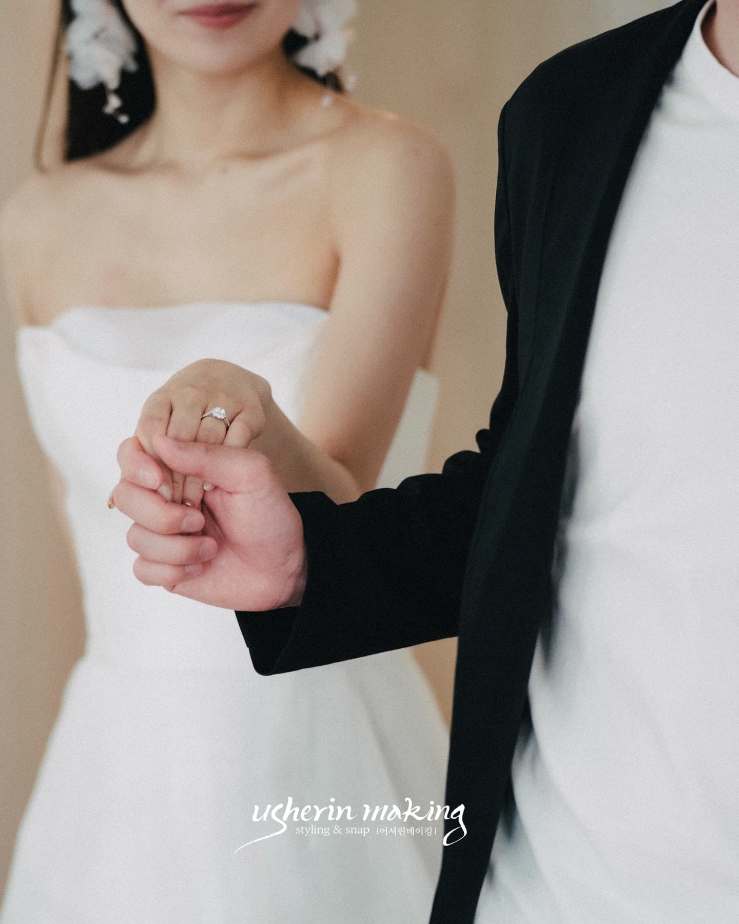 Close-up of the groom gently holding the bride's ring hand in the studio