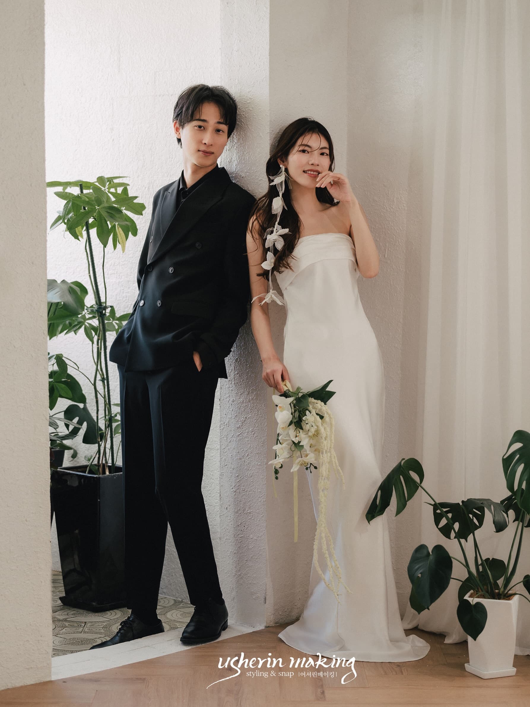 Smiling couple with a white bouquet in a plant-filled bright studio