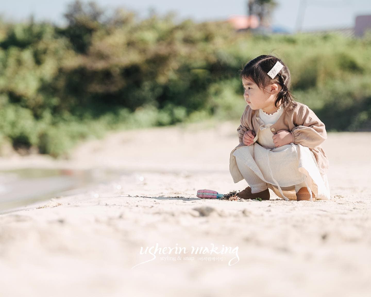 晴れた沖縄の浜辺にしゃがんで遊ぶ小さな女の子