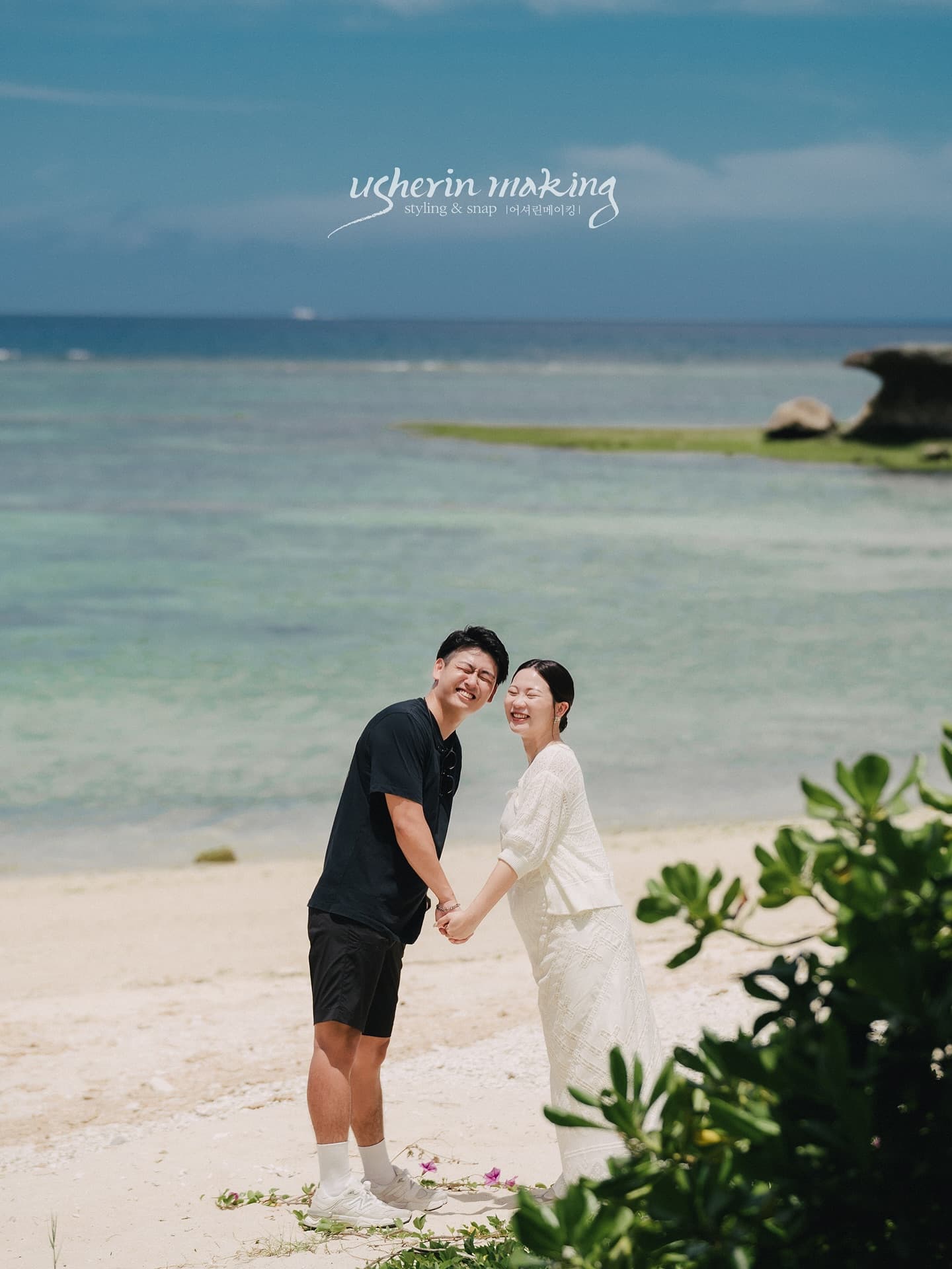Couple laughing hand in hand on a white-sand beach by emerald sea, Okinawa
